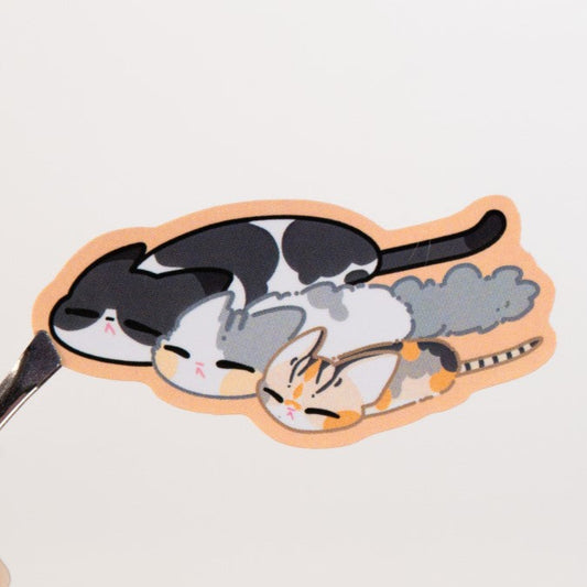 Sticker with cat design held by a hand on a light background