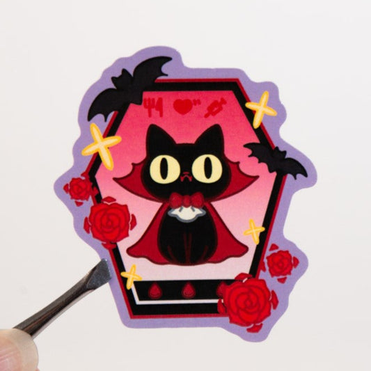 Sticker of a black cat in a coffin with roses on a white background
